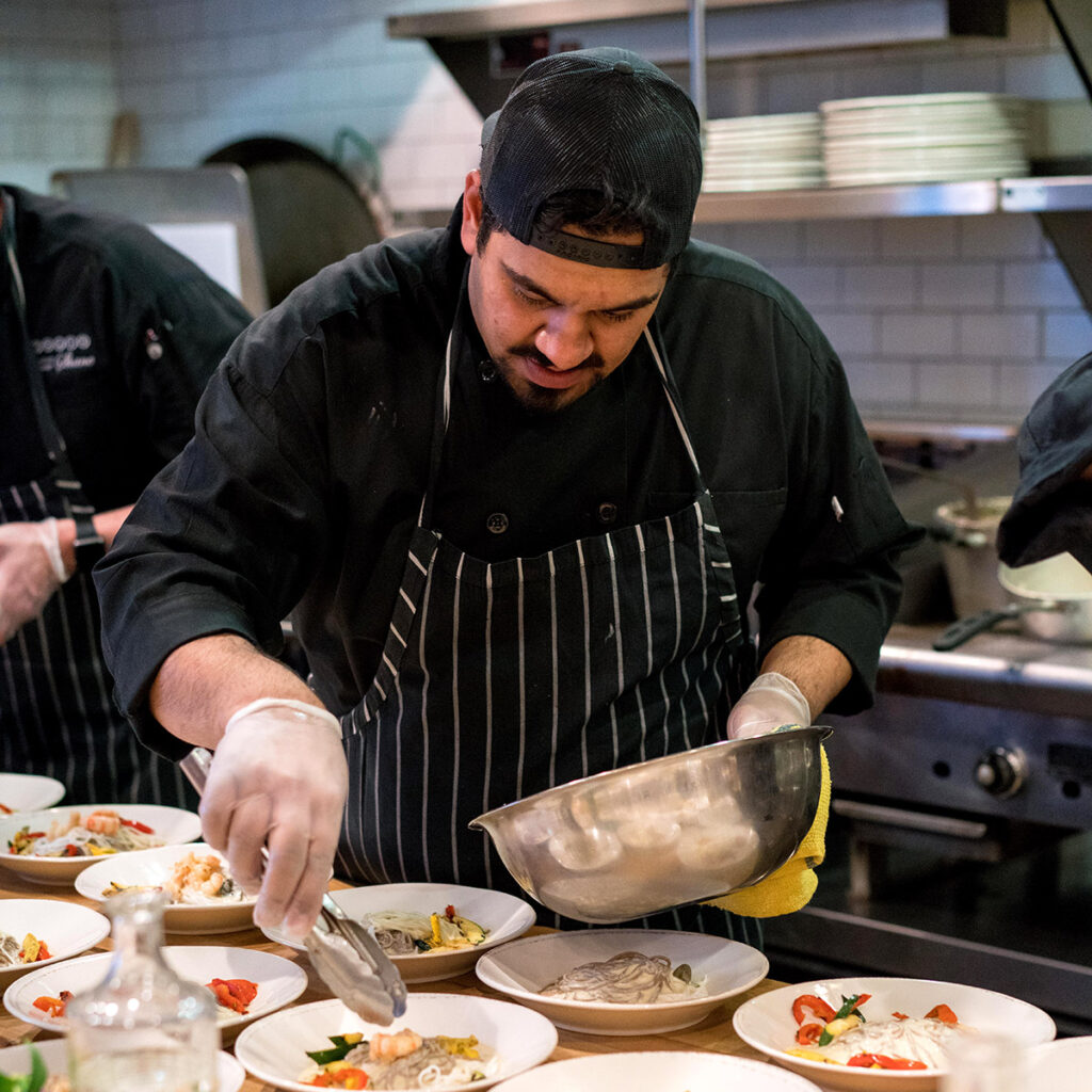 Chef plating cuisine onto white plates